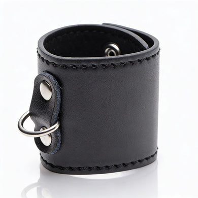 Black leather-style 2-inch ball stretcher cuff with silver D-ring attachment and smooth stitched finish