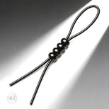 4-Way Adjustable Cock and Ball Tie with black cord and sliding beads, flexible design for adjustable tension and secure fit