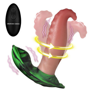 A vibrating tongue shown on a white background, featuring a realistic pink and reddish-brown curved shaft with yellow rotation arrows, a green flared base, and a black remote control labeled 'CREATURE COCKS' in the upper left.