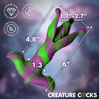 A 3D render of a novelty cock-shaped product with green and purple coloration, overlaid with dimension lines and text showing measurements for closed and open states, plus badges reading premium silicone, phthalate free, and nickel free. 