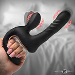 A black dual-stimulation personal massager with a curved handle and two flexible shafts, held by a hand against a blurred bedroom background. Red wavy lines indicate stimulation points.