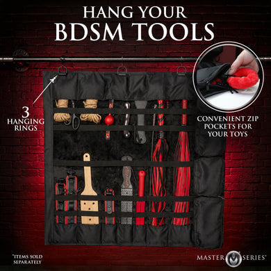 Black multi-tool hanging organizer with multiple zip pockets and three hanging rings, shown against a dark red brick background with text reading 'HANG YOUR BDSM TOOLS' and feature callouts.