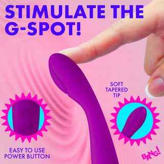 A purple curved personal massager being held by a hand against a pink graphic background with promotional text reading 'STIMULATE THE G-SPOT!' and feature callouts including 'SOFT TAPERED TIP' and 'EASY TO USE POWER BUTTON'.