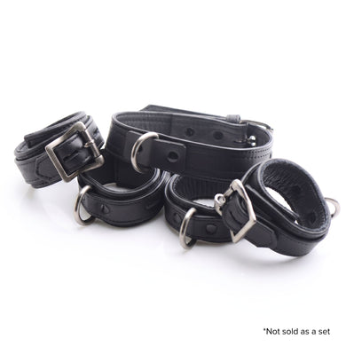 Assortment of black locking collars and cuffs featuring padded interiors, adjustable buckles, and metal D-ring attachments displayed together on a white background