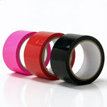 Bondage tape rolls in pink, red, and black displayed together to showcase available color options for self-adhesive restraint play tape