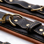 Close-up of Coax collar to wrist restraints showing textured faux leather, reinforced stitching, antique gold rings, and chain clips