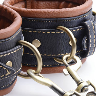 Detailed view of padded Coax collar to wrist restraints cuffs with antique gold O-rings, adjustable buckles, and soft brown lining