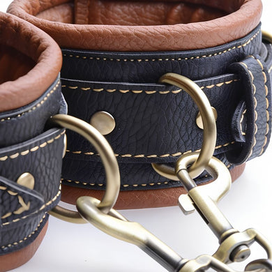 Detailed view of padded Coax collar to wrist restraints cuffs with antique gold O-rings, adjustable buckles, and soft brown lining