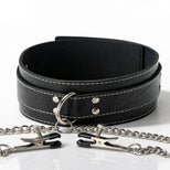 Close-up of a black bondage collar featuring decorative stitching, metal O-ring, chain attachment, and adjustable nipple clamps