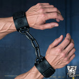 Leather Wrist Cuffs locked on both wrists and linked by a black chain at the D-rings