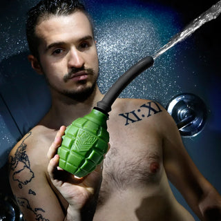 Grenade anal douche bulb spraying water, held by a model in the shower, Fort Troff