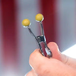 Hand squeezing a Captive Grip nipple clamp open by its wide handles, Fort Troff