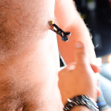 Captive Grip nipple clamp hanging from a nipple while a hand tugs it, Fort Troff