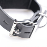 Detailed view of the adjustable buckle and strap construction on a black bondage restraint cuff