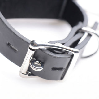 Detailed view of the adjustable buckle and strap construction on a black bondage restraint cuff