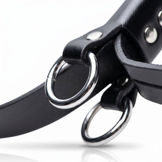 Close-up of reinforced metal attachment rings mounted on black bondage cuff straps