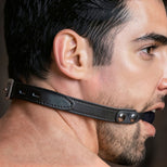 Locking silicone ball gag fastened with its leather strap for BDSM mouth restraint