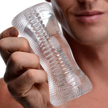 Male model holding the Palm-Tec DX17 Clear Stroker featuring a transparent body, ribbed internal texture, and ergonomic hourglass shape