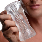 Male model holding the Palm-Tec DX17 Clear Stroker featuring a transparent body, ribbed internal texture, and ergonomic hourglass shape