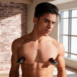 Male model wearing black vibrating nipple suckers with metallic accents, demonstrating fit and placement on the chest