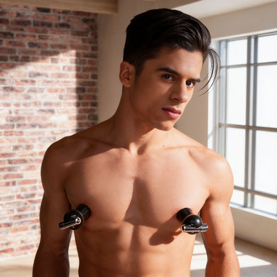 Male model wearing black vibrating nipple suckers with metallic accents, demonstrating fit and placement on the chest