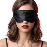 Woman wearing black satin blindfold eye mask, showcasing smooth fabric and full light-blocking coverage
