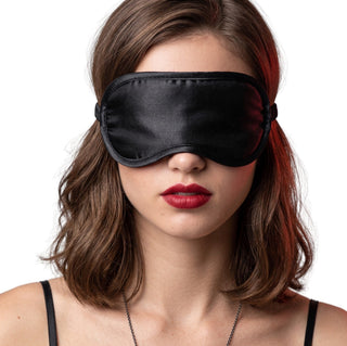 Woman wearing black satin blindfold eye mask, showcasing smooth fabric and full light-blocking coverage

