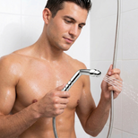 Man holding a chrome shower enema wand attached to a flexible shower hose with water flowing from the nozzle in a shower setting