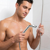 Man holding a chrome shower enema wand attached to a flexible shower hose with water flowing from the nozzle in a shower setting