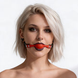 Female model with platinum blonde hair wearing a black faux leather gag with bright red silicone comfort ball