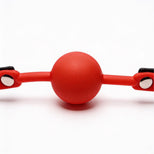 Close-up front view of bright red silicone comfort ball attached to a black faux leather gag strap