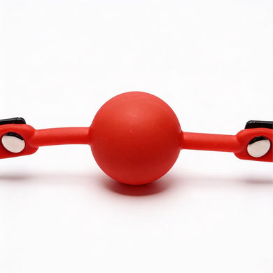 Close-up front view of bright red silicone comfort ball attached to a black faux leather gag strap