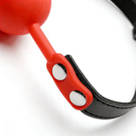 Detail shot of red silicone strap connection with silver rivets attached to black faux leather gag collar