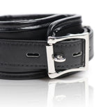 Close-up of the adjustable buckle on a padded black restraint cuff with polished metal hardware
