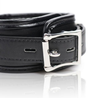 Close-up of the adjustable buckle on a padded black restraint cuff with polished metal hardware