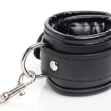 Detailed view of a padded black restraint cuff featuring a metal D-ring, swivel clasp, and reinforced rivet construction