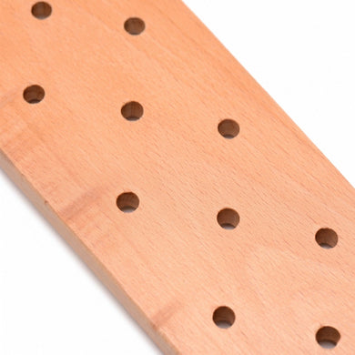 Close-up of the perforated wooden striking surface showing smooth craftsmanship and evenly spaced airflow holes